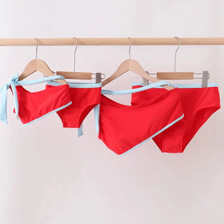 Red bikini set with blue straps on a wooden hanger against a white background