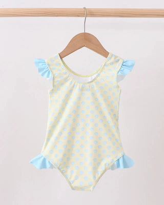 Yellow seashell print swimsuit with blue trim on a wooden hanger against a light gray background