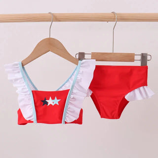 Red bikini set with white ruffles on a wooden hanger against a light gray background