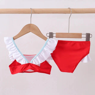 Red bikini with white ruffle details on a wooden hanger against a light background