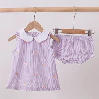 Children's outfit with a dress and bloomers on hangers against a light background