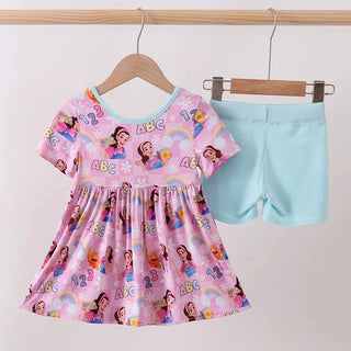 Children's pink dress with cartoon characters and blue shorts on a hanger against a white background