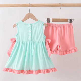 Children's outfit with mint green dress and pink shorts on hangers against a white background