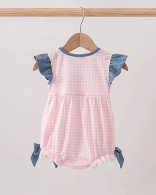 Pink checkered romper with blue ruffled sleeves on a wooden hanger against a light gray background