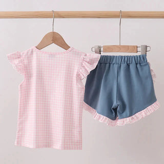 Pink checkered top and blue shorts with ruffled hem on hangers against a light gray background