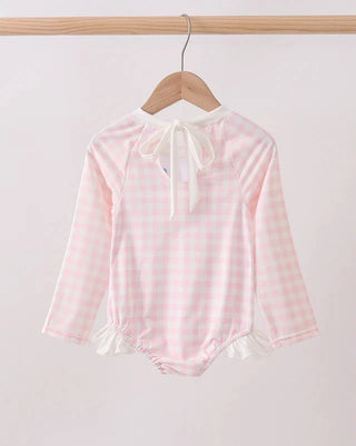Pink checkered baby outfit with long sleeves on a wooden hanger against a white background