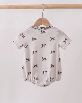Baby romper with bird pattern on a hanger against a white background