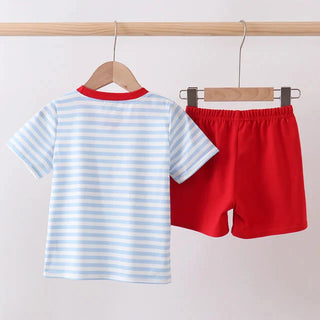 Children's striped shirt and red shorts hanging on a wooden rod against a white background
