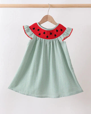 Children's dress with watermelon design on a hanger against a white background