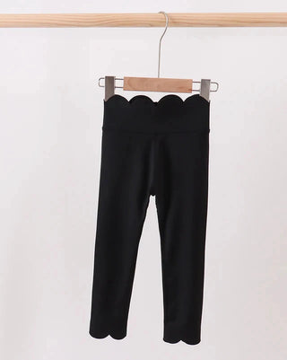 Black pants hanging on a wooden hanger against a white background