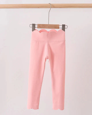 Pink leggings hanging on a wooden hanger against a light pink background