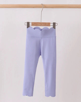 Light purple pants hanging on a wooden hanger against a white background