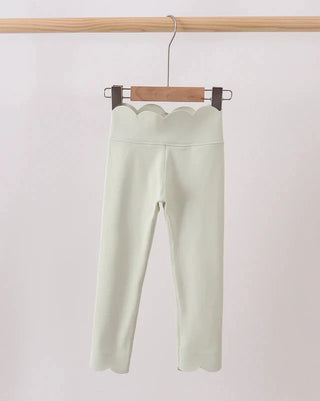 Light green pants hanging on a wooden hanger against a white background