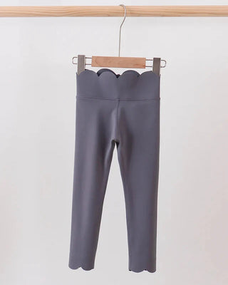 Gray leggings hanging on a wooden hanger against a white background