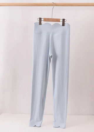 Light blue pants hanging on a wooden hanger against a white background