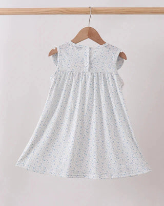 White dress with subtle pattern on a wooden hanger against a plain background
