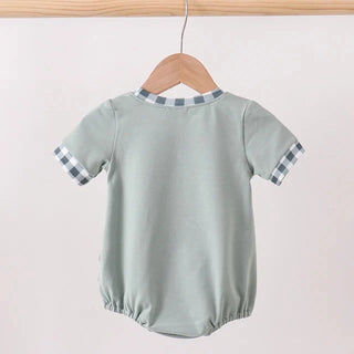 Light green baby romper with checkered sleeves on a wooden hanger against a white background
