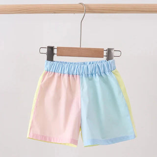 Pastel-colored shorts hanging on a wooden rod against a light background