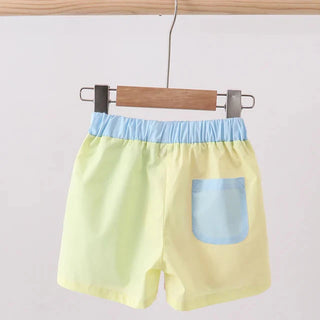 Yellow shorts with blue waistband and pocket on a hanger against a light gray background