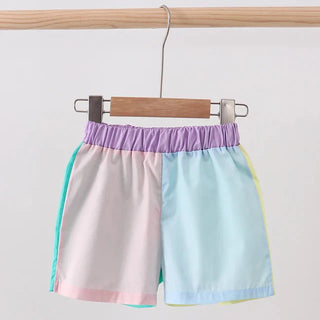 Colorful shorts hanging on a wooden rod against a white background