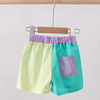 Color-blocked shorts with yellow, green, and purple on a hanger against a white background