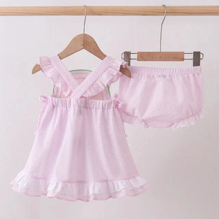 Pink baby outfit with top and shorts on hangers against a white background