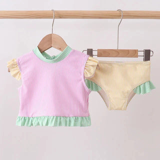 Children's swimsuit set with pink top and yellow bottom on a wooden hanger against a white background