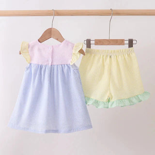 Pastel top and shorts set on hangers against a light pink background
