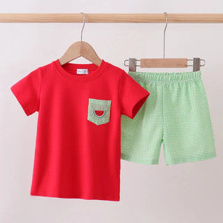 Red t-shirt with a pocket and green checkered shorts on hangers against a white background