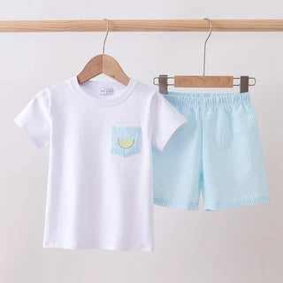 White t-shirt with a small pocket design and light blue shorts on hangers against a plain background