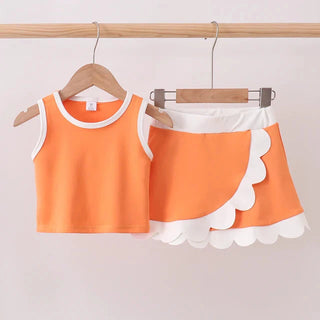 Orange tank top with white scalloped hem on a hanger against a plain background