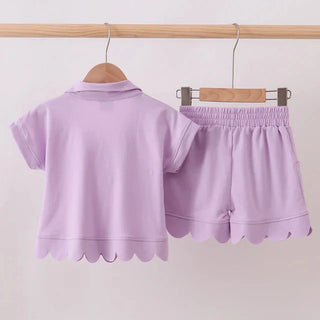 Lavender children's outfit with top and shorts on hangers against a white background