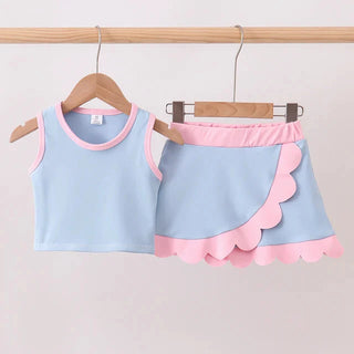 Children's blue and pink outfit with a top and shorts on hangers against a plain background