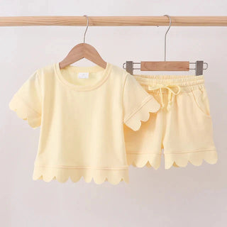 Yellow children's outfit with a top and shorts on hangers against a white background