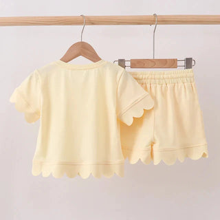 Yellow outfit with a top and shorts on hangers against a white background
