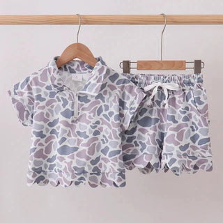 Children's outfit with patterned shirt and shorts on hangers against a white background