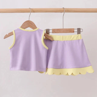 A two-piece children's outfit set consisting of a sleeveless top and a skirt in light purple with yellow trim, hanging on wooden hangers from a wooden clothes rack against a plain light background.