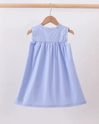 A light blue sleeveless dress with ruffled trim at the neckline, hanging on a wooden hanger from a wooden clothes rack against a plain white background.