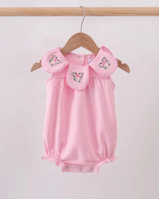A baby girl's pink sleeveless romper with a large ruffled collar decorated with butterfly appliques, hanging on a wooden hanger against a light gray background.