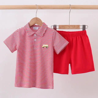 A children's two-piece outfit hanging on wooden hangers against a plain light background. The set includes a short-sleeve polo shirt with thin red and white vertical stripes and a small embroidered bus motif on the chest, paired with solid bright red shorts.