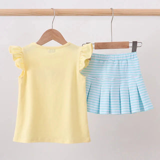 A two-piece girls' outfit set hanging on wooden hangers from a light wood rod. The set includes a pale yellow short-sleeve top with ruffled sleeves and a light blue and white striped pleated mini skirt.