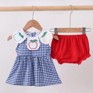 A baby girl's two-piece outfit hanging on wooden hangers against a plain light background. The set includes a blue and white gingham check dress with a white collar decorated with embroidered apple motifs, and a pair of bright red bloomers.