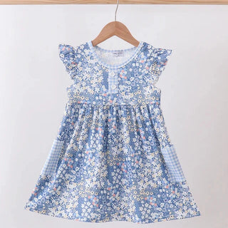 A blue and white floral print baby dress with flutter sleeves and a smocked bodice, hanging on a wooden hanger against a plain white wall.