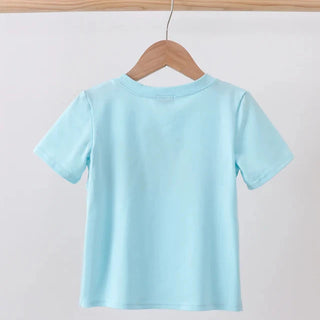 A light blue short-sleeve t-shirt hanging on a wooden hanger from a wooden clothes rack against a plain light gray background.