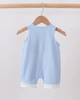 A light blue sleeveless baby romper hanging on a wooden hanger from a wooden clothes rack against a plain light background.