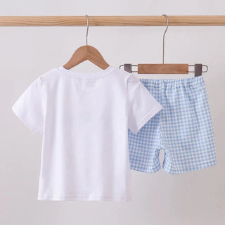 A two-piece children's outfit set hanging on wooden hangers from a light wood rod. The set includes a plain white short-sleeve t-shirt and light blue and white gingham check shorts.
