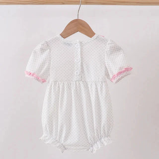 White baby romper with pink trim on a wooden hanger against a light gray background