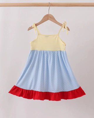 A toddler girl's sleeveless dress hanging on a wooden hanger against a light beige wall. The dress has a pale yellow ribbed bodice, a light blue polka-dot skirt, and a contrasting red ruffled hem.