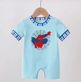 A baby short-sleeve romper in light blue, hanging on a wooden hanger. The romper features a Spider-Man graphic on the chest and blue-and-white checkered trim on the collar and cuffs.