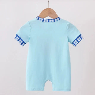 A light blue baby romper with blue and white gingham trim on the collar and sleeve cuffs, hanging on a wooden hanger from a wooden clothes rack against a plain off-white background.
